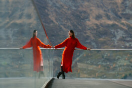 red-dress-woman-reflection-in-glass-symmetry-alpine-background 