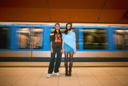 two-female-friends-holding-hands-subway-station-train-whizzes-by-urban-streetwear 