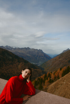 woman-red-dress-leaning-peaceful-look-into-camera-mountain-environment 